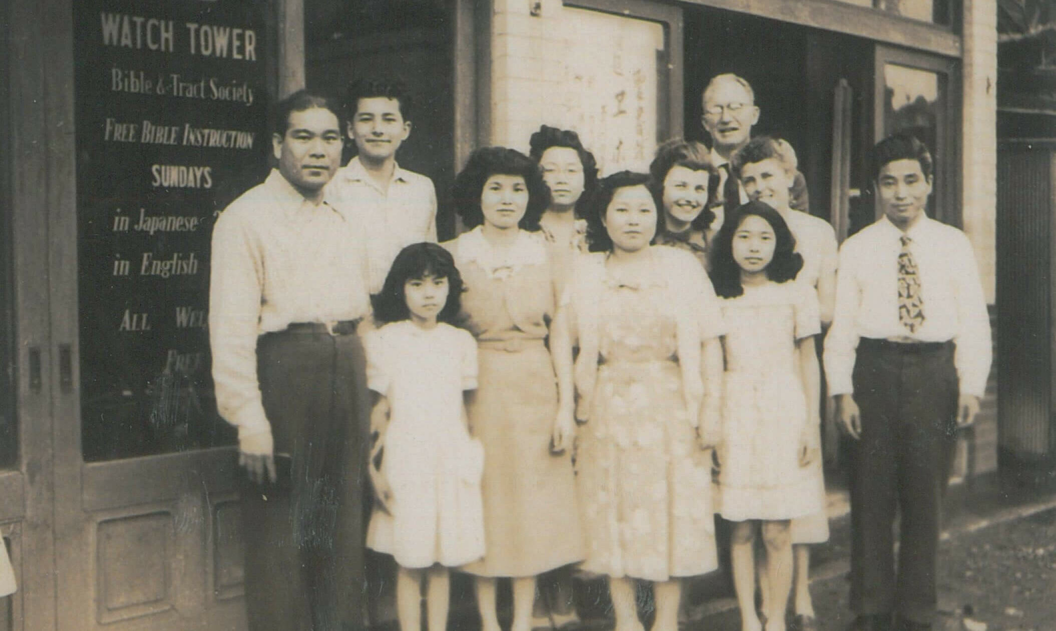 a group of people standing in front of a building marked Watch Tower Bible & Tract Society