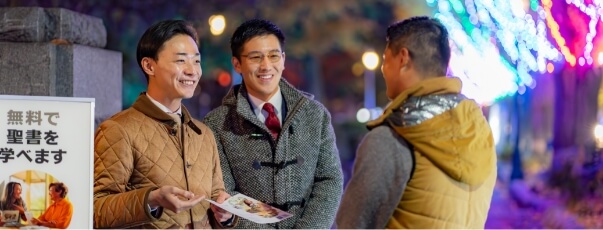 two men standing in front of a public witnessing cart smiling and conversing with a man
